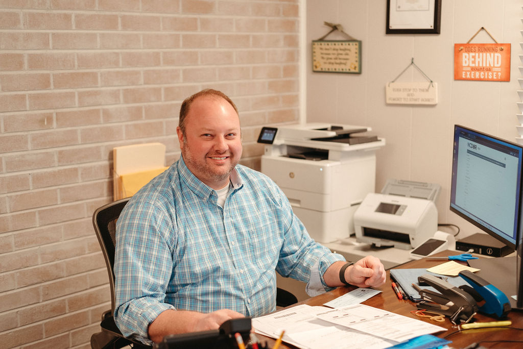 Jayson Snipes, CPA, EA, smiling at his desk in the Snipes Tax office